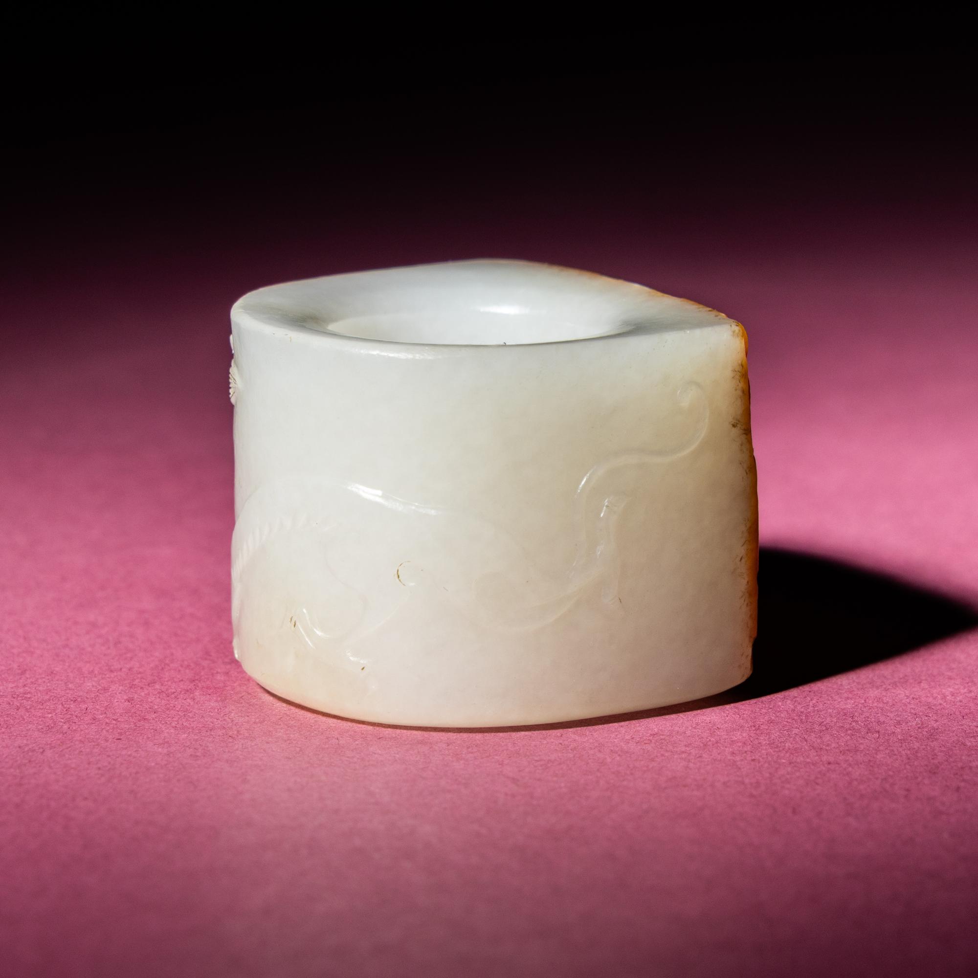 A Chinese Russet and White Jade 'Taotie and Chilong' Archer's Ring, 18th Century — 清中期 白玉留皮饕餮螭龍紋扳指
