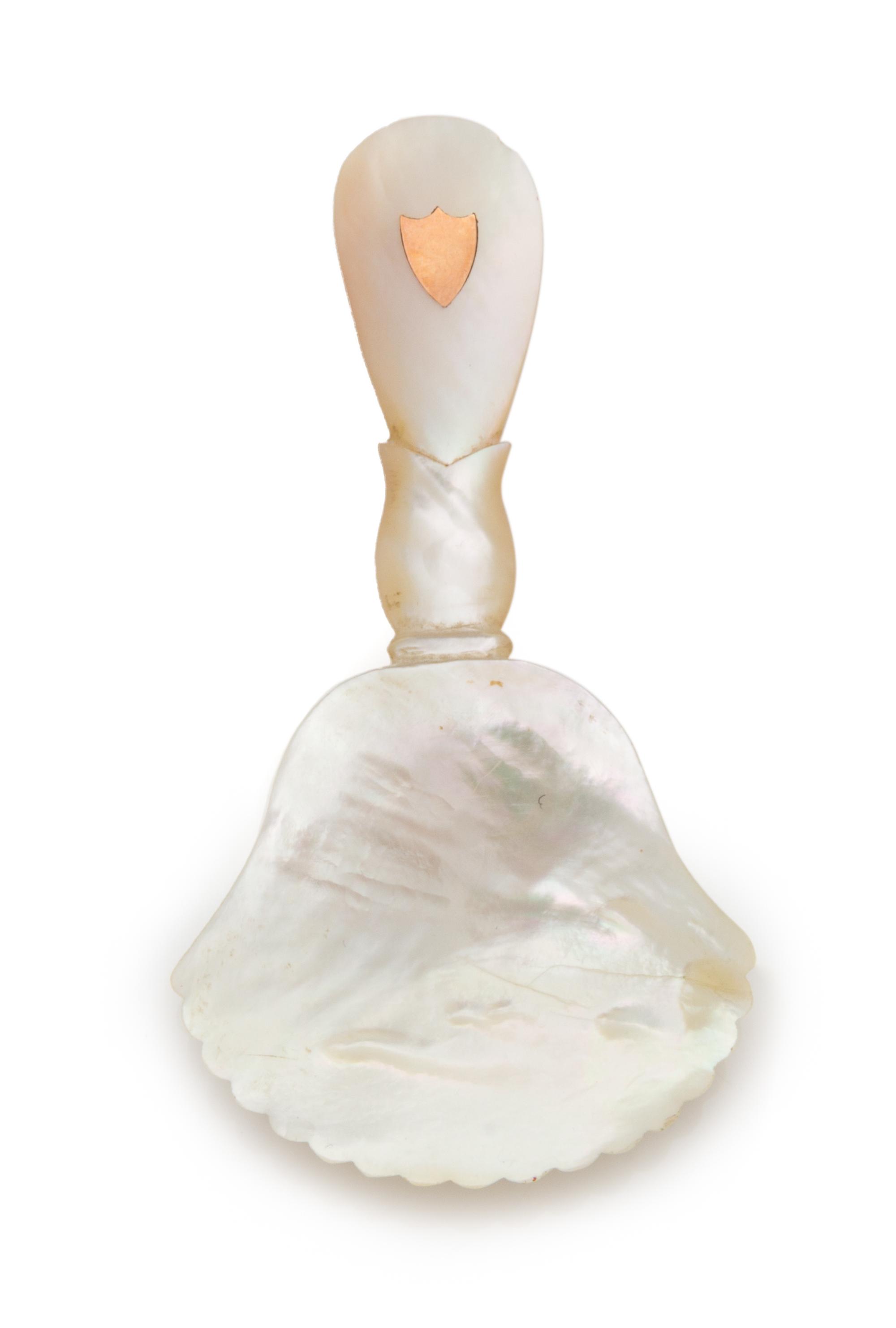 A Palais Royal Mother-of-Pearl Caviar Spoon, , having a scallop-form bowl, the handle with an inset git-metal shield cartouche.
