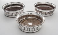 Three Sheffield-plate Wine Coasters, Probably 19th Century, with beaded rims and wood centers, two engraved in center with arm and arro
