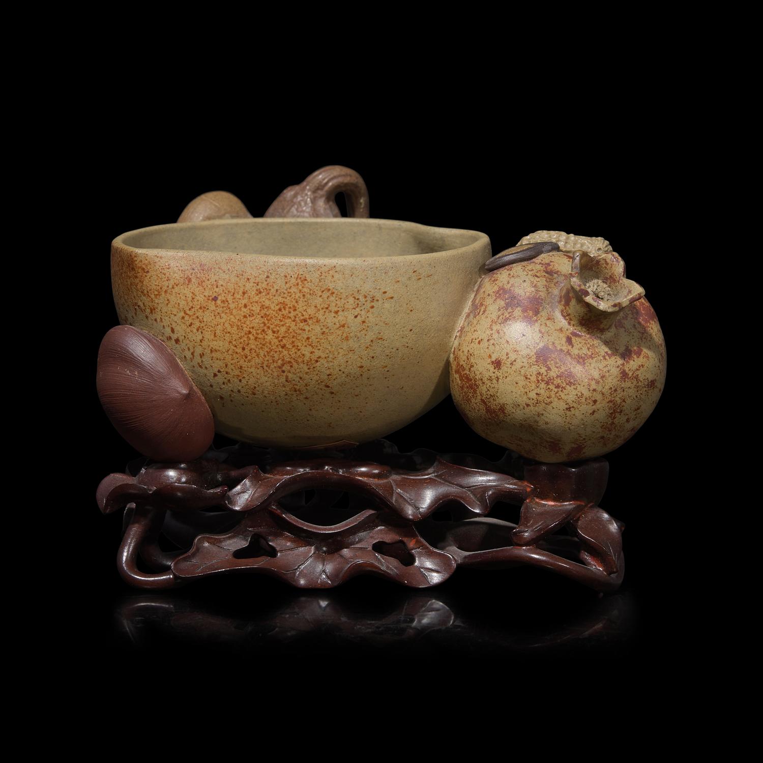 A Rare Chinese Yixing 'Peach and Pomegranate' Coupe Inscribed 'Chen Minyuan Zuo' and Carved Wood Stand 陳鳴遠款段泥紫砂桃榴杯