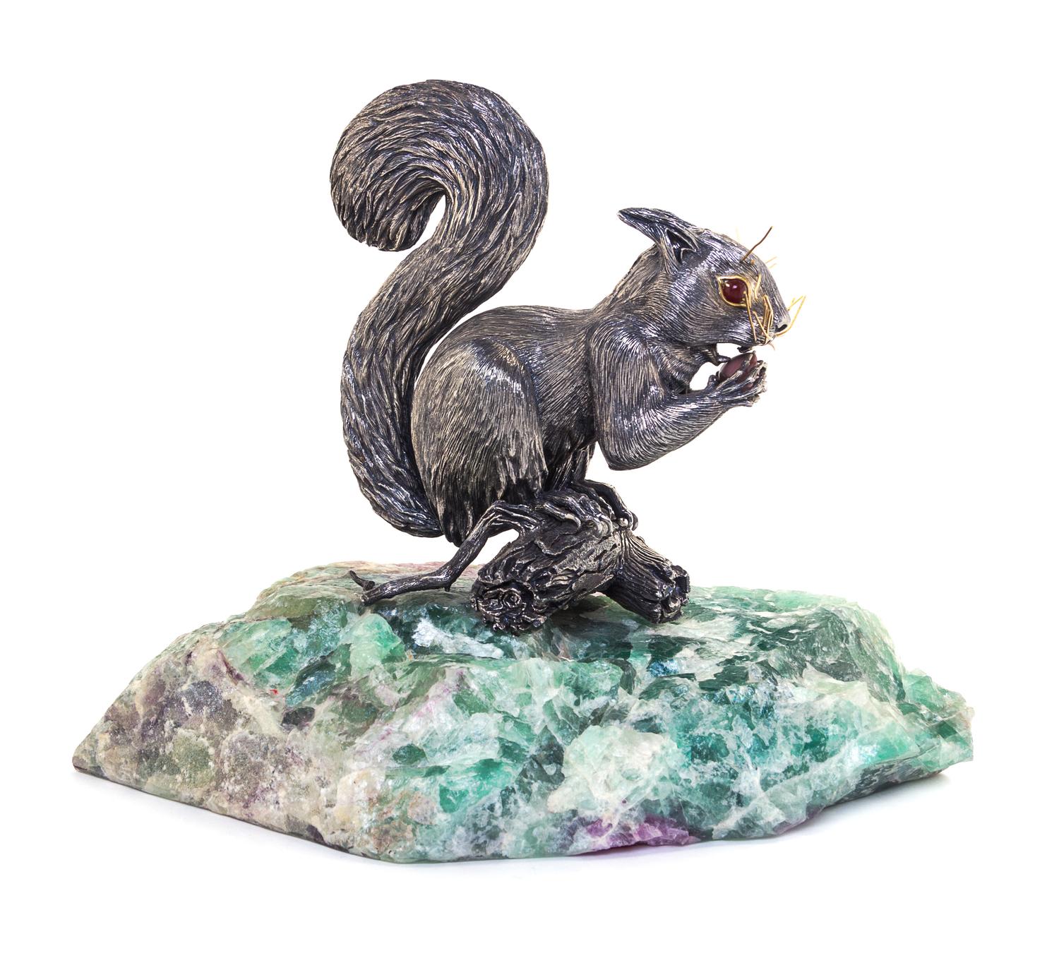 A Italian Silver Model of a Squirrel, 20th Century, depicted seated on a branch eating a nut, set on a quartz base.