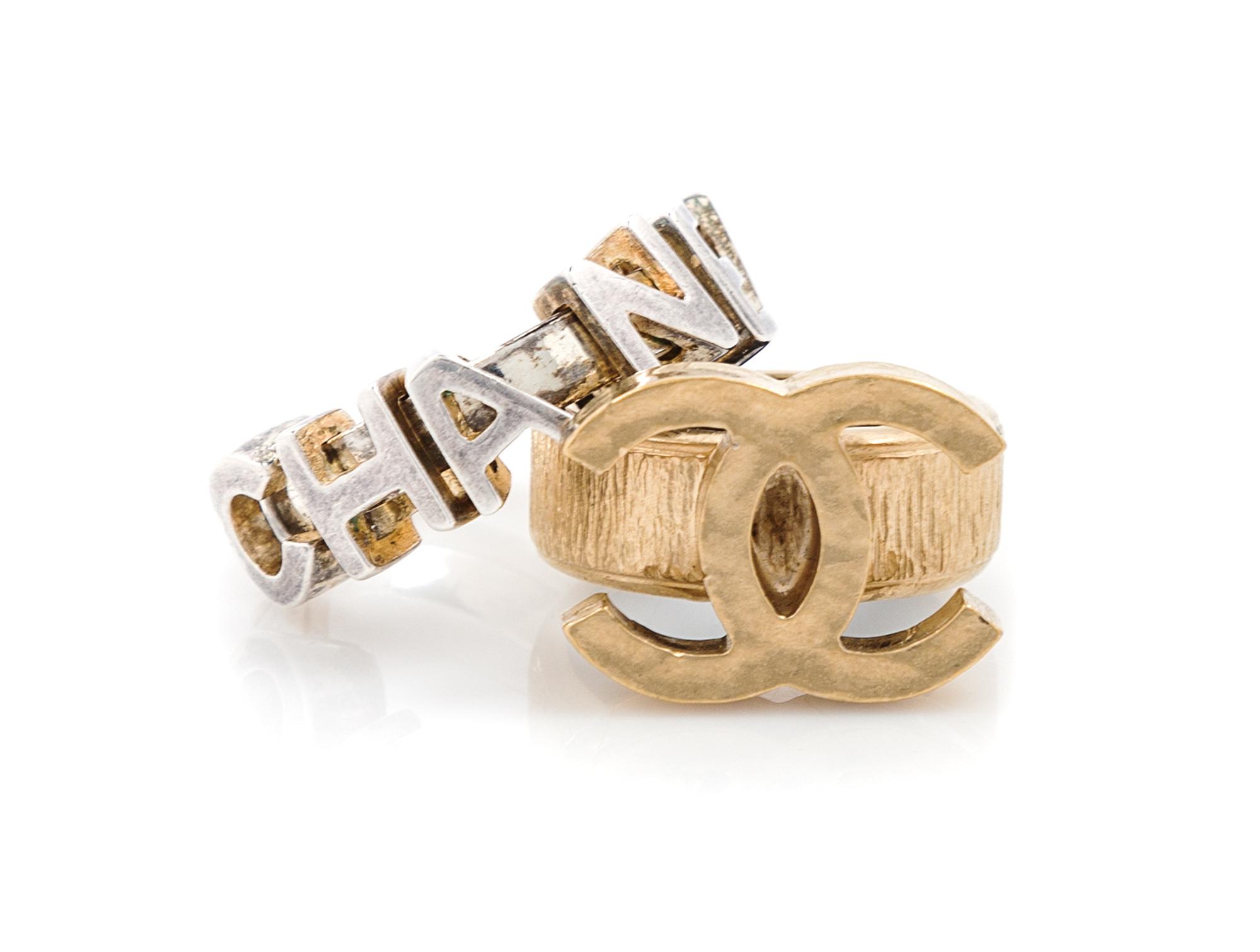 A Pair of Chanel Rings, Goldtone CC size: 6 1/4; Silvertone charm size: 6 1/4.