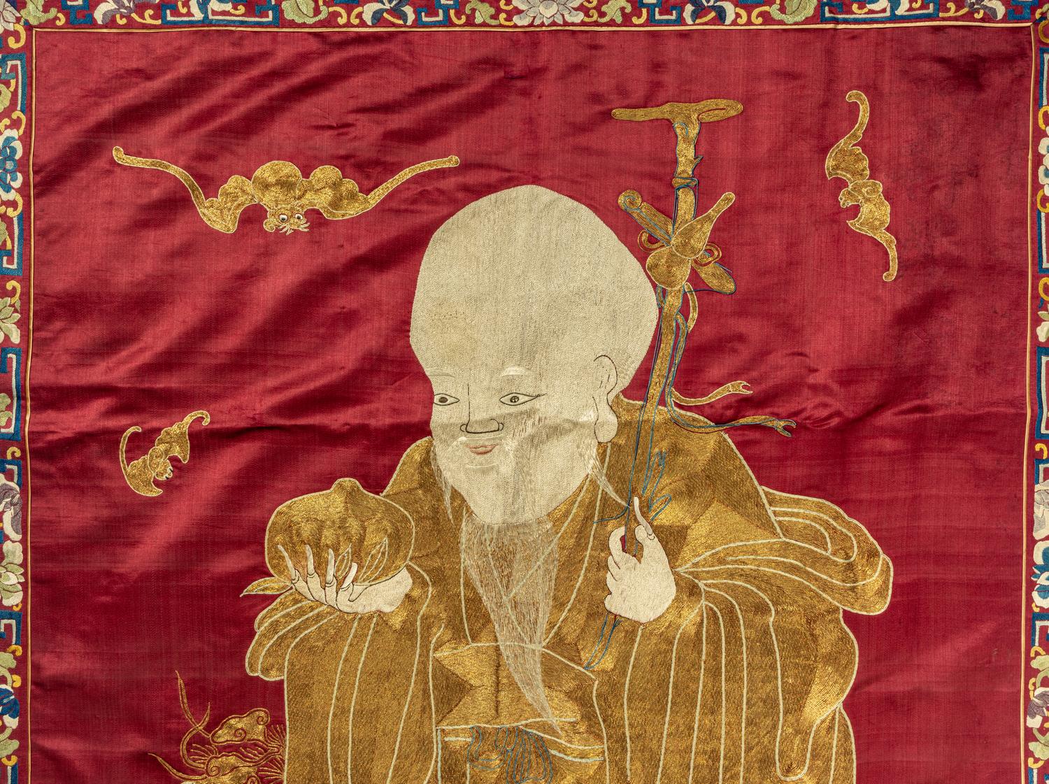 A Large Chinese Red Ground Embroidered Silk 'Longevity' Panel