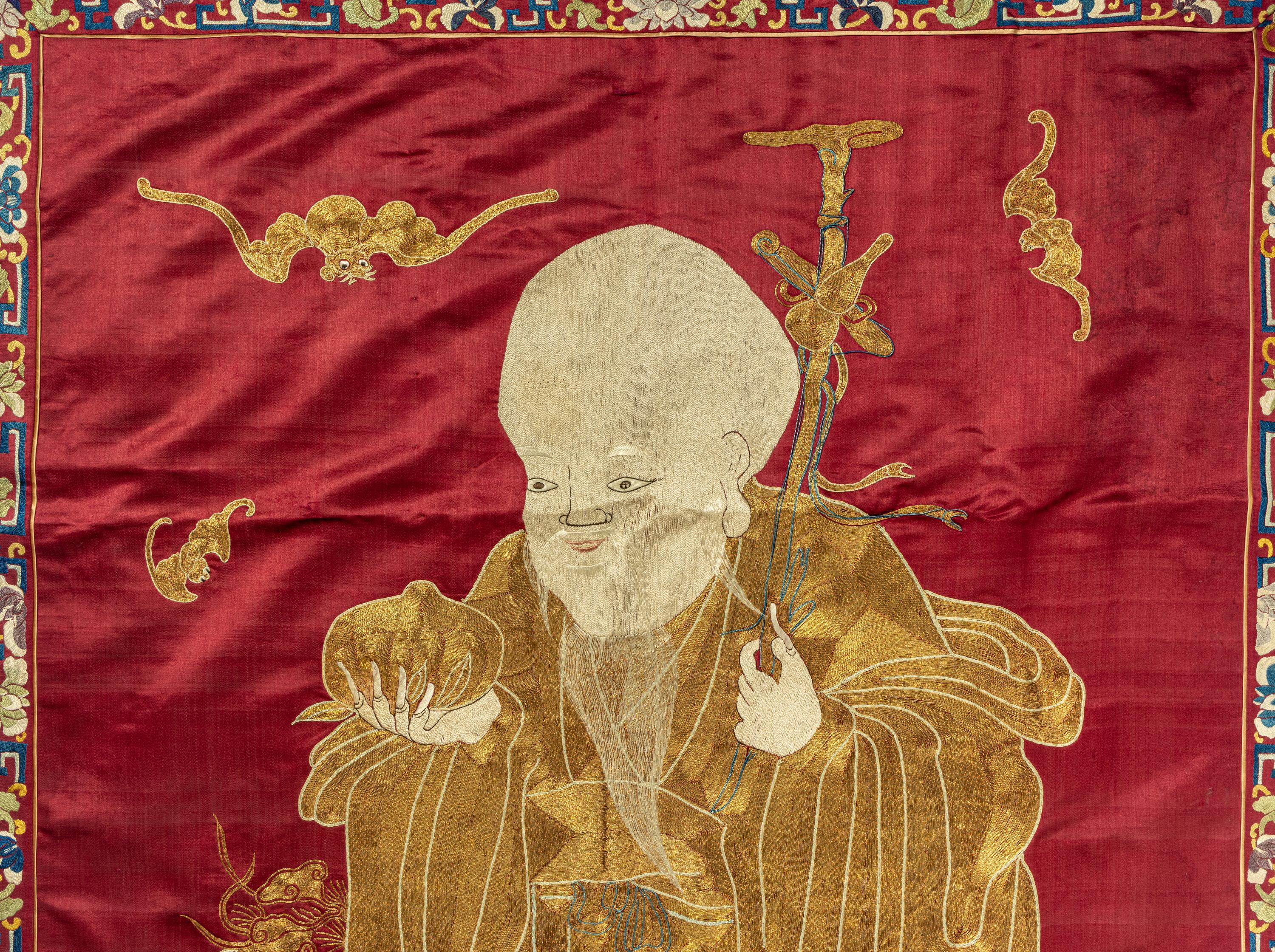 A Large Chinese Red Ground Embroidered Silk 'Longevity' Panel