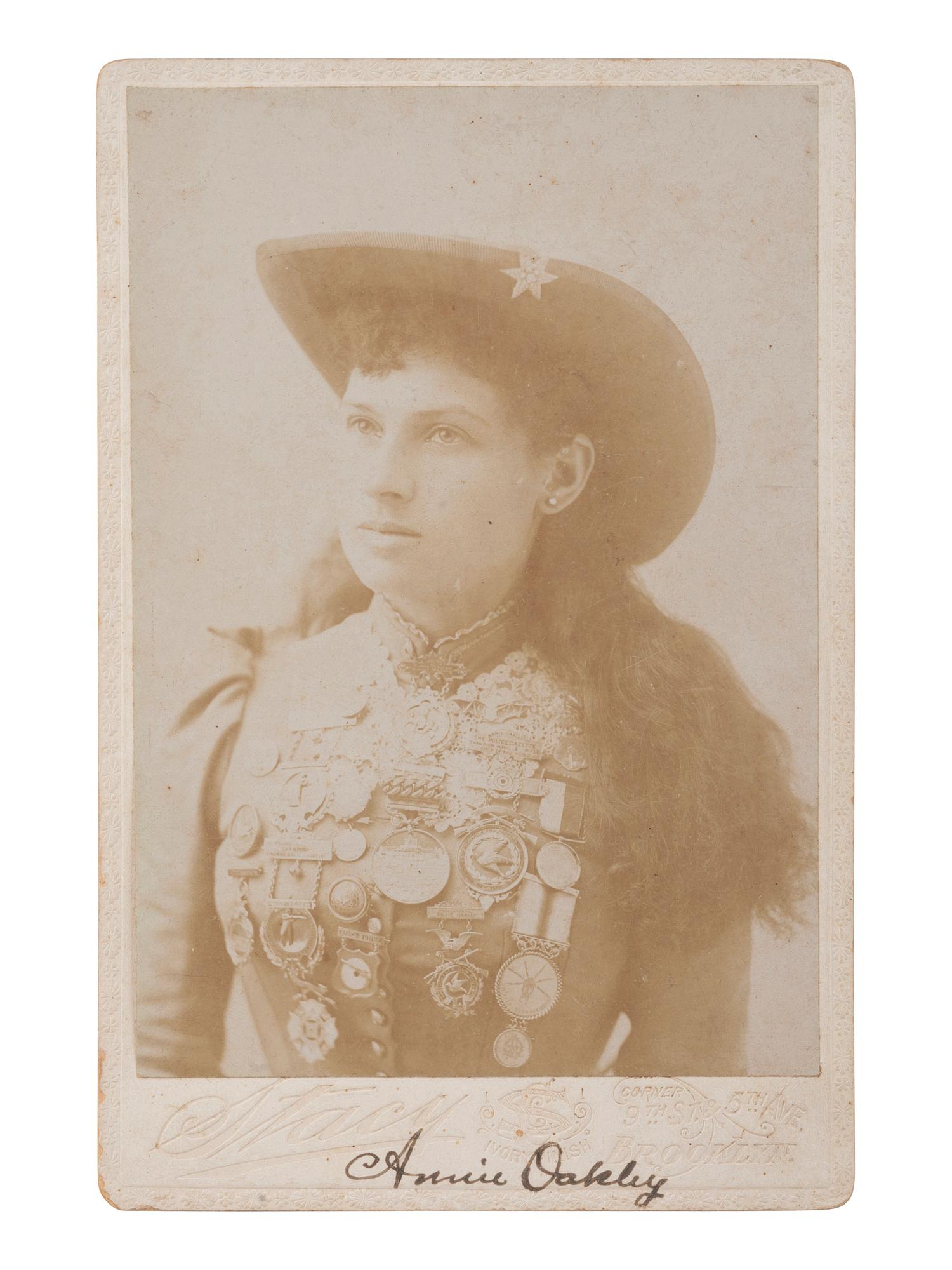 [OAKLEY, Annie (1860-1926)]. Cabinet card portrait of Annie Oakley wearing her shooting medals. New York: Stacy, ca 1890s.
