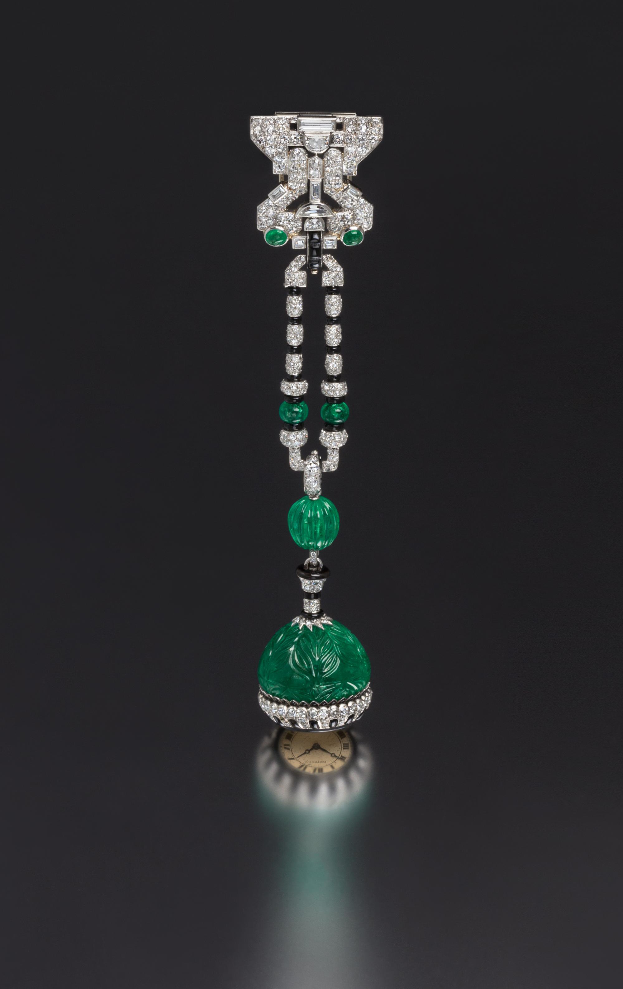 An Art Deco Platinum, Emerald, Diamond, Onyx and Enamel Lapel Watch, Cartier, 37.00 dwts.