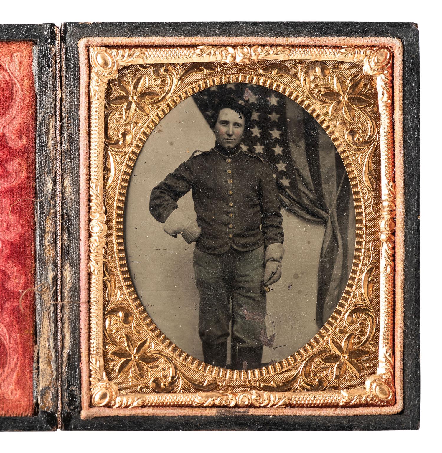 [CIVIL WAR]. Sixth plate tintype of a uniformed soldier standing before a large American flag.