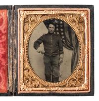 [CIVIL WAR]. Sixth plate tintype of a uniformed soldier standing before a large American flag.