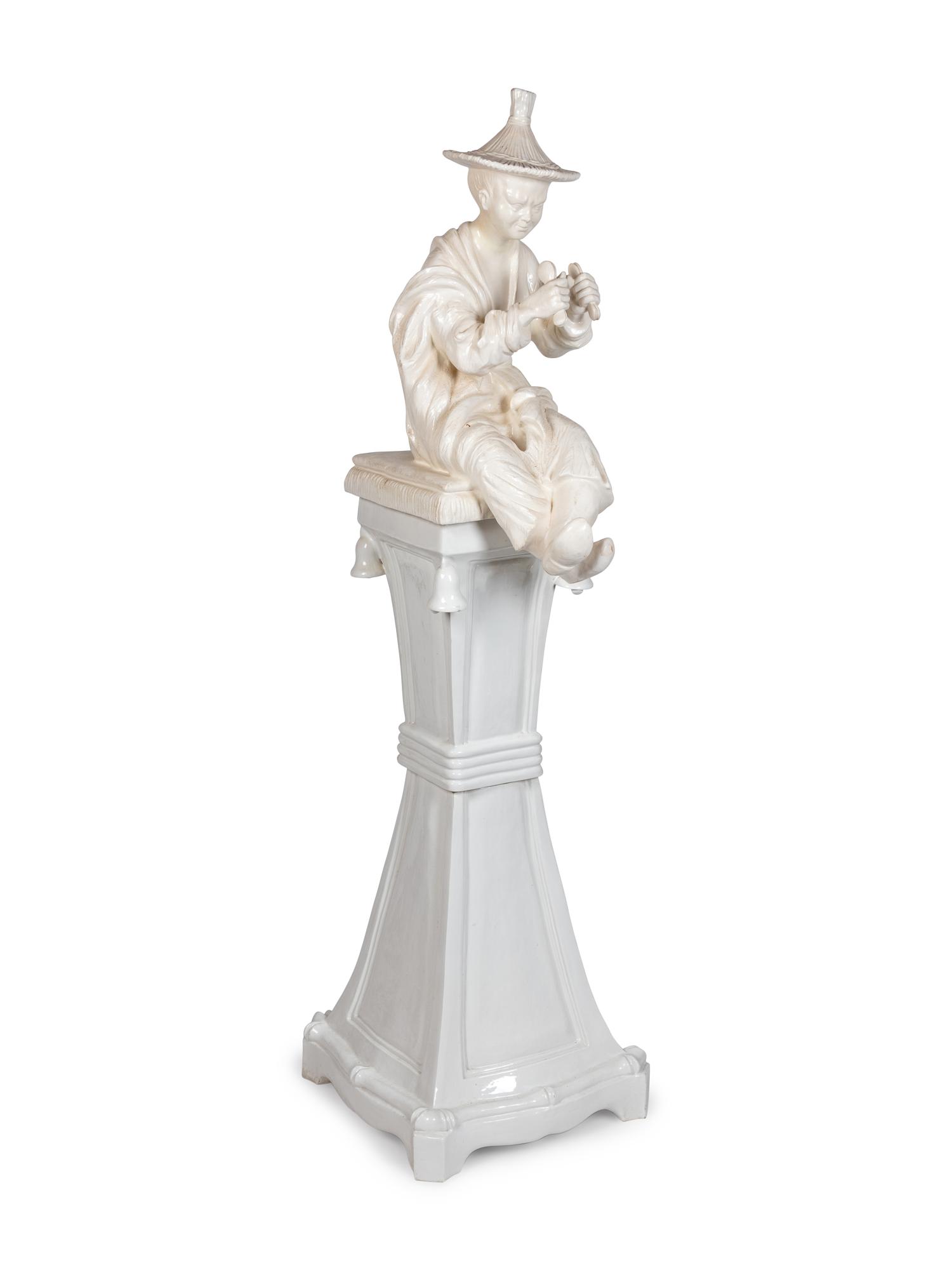 A Continental Blanc de Chine Figure of a Seated Chinese Man on a Pedestal
