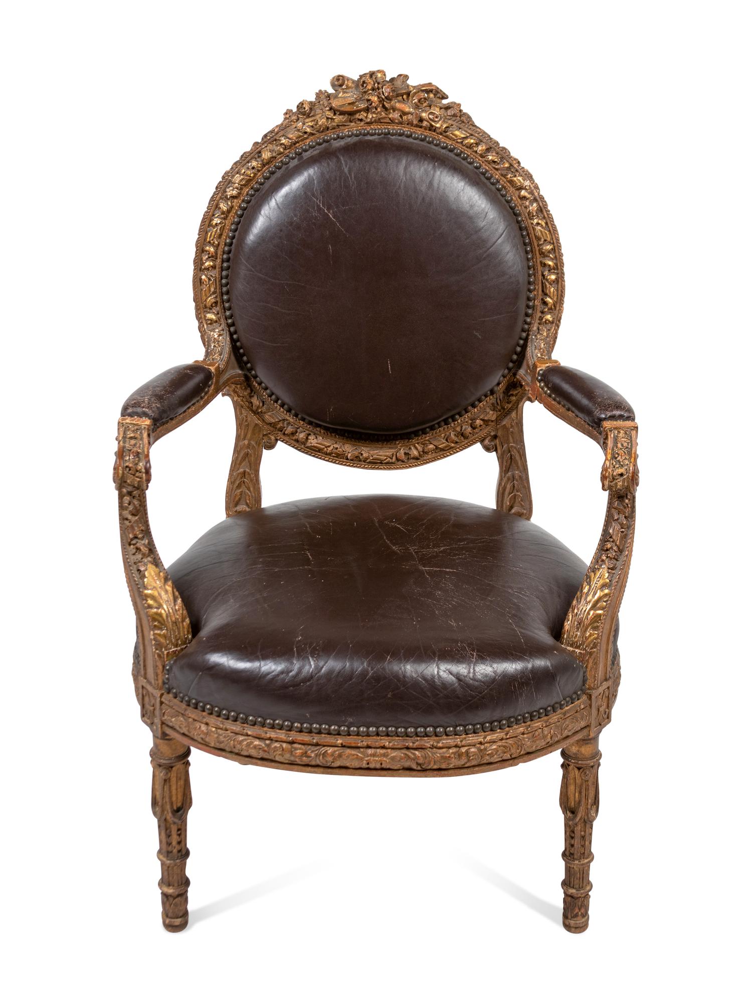 A Louis XVI Style Leather Upholstered and Parcel Gilt Fauteuil