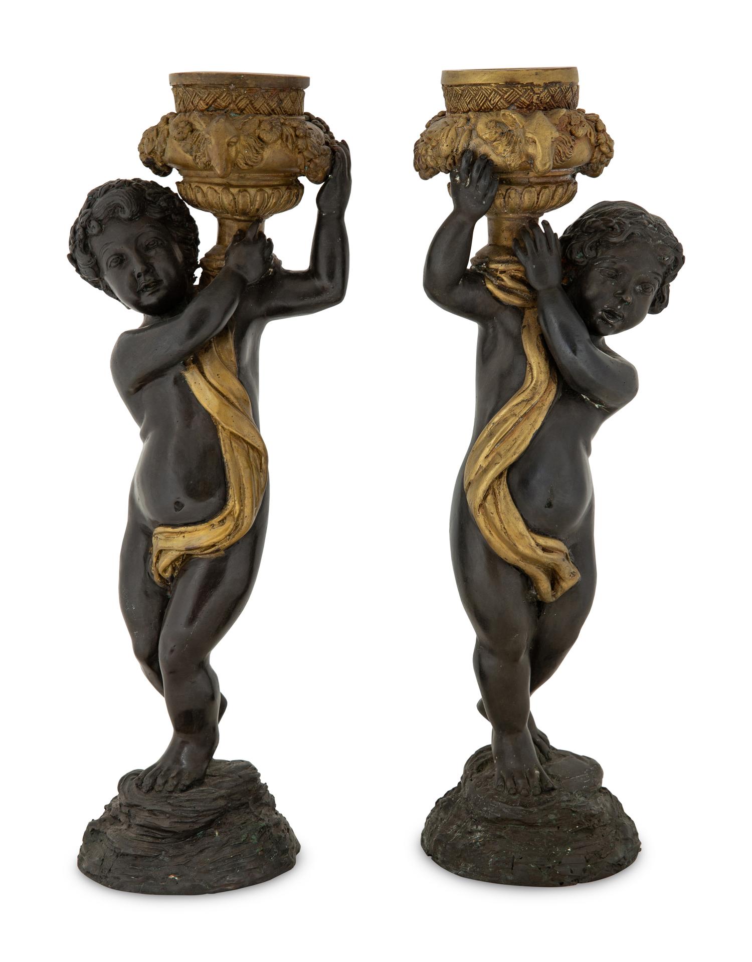 A Pair of Parcel Gilt Cast Metal Putti Candlesticks