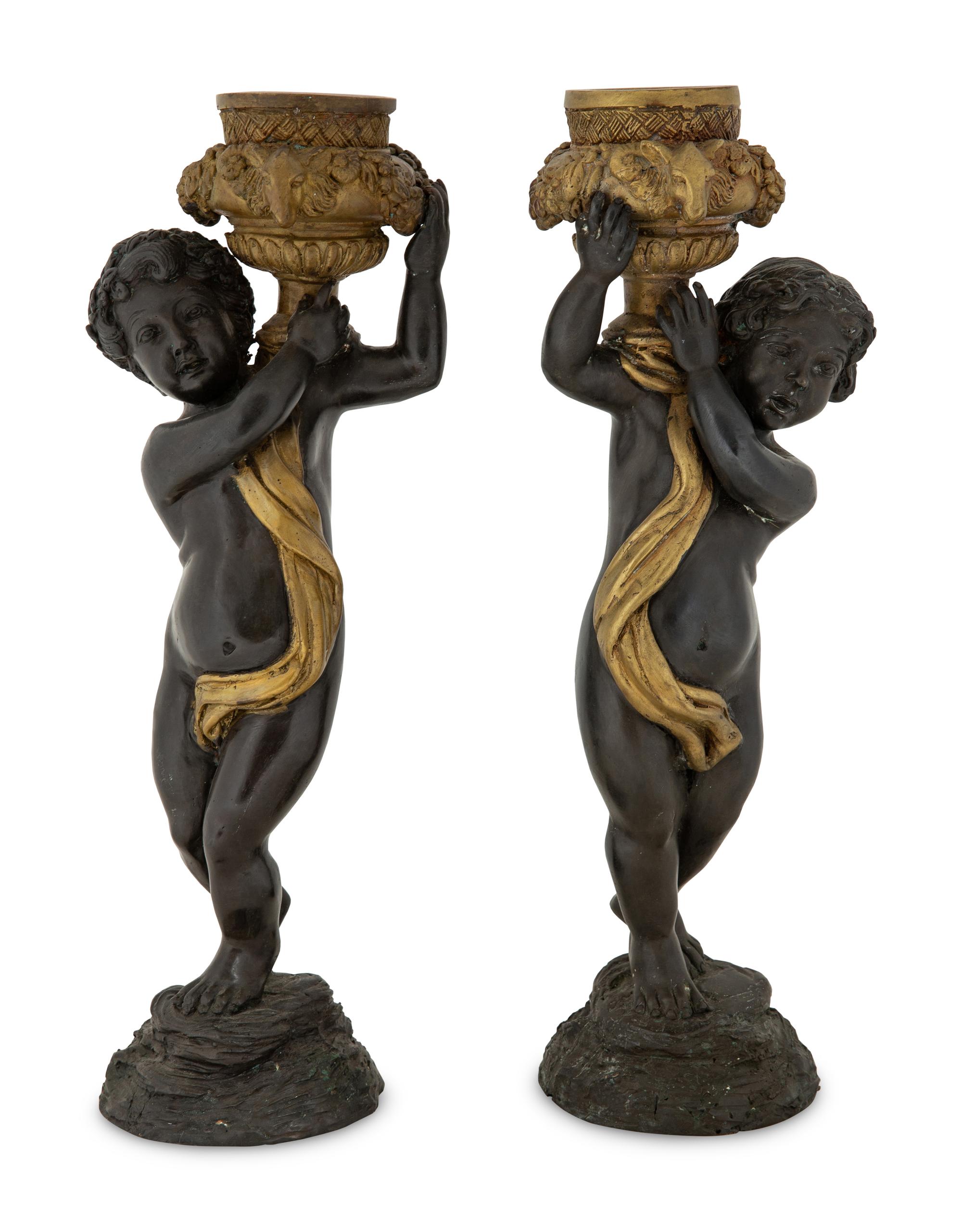 A Pair of Parcel Gilt Cast Metal Putti Candlesticks