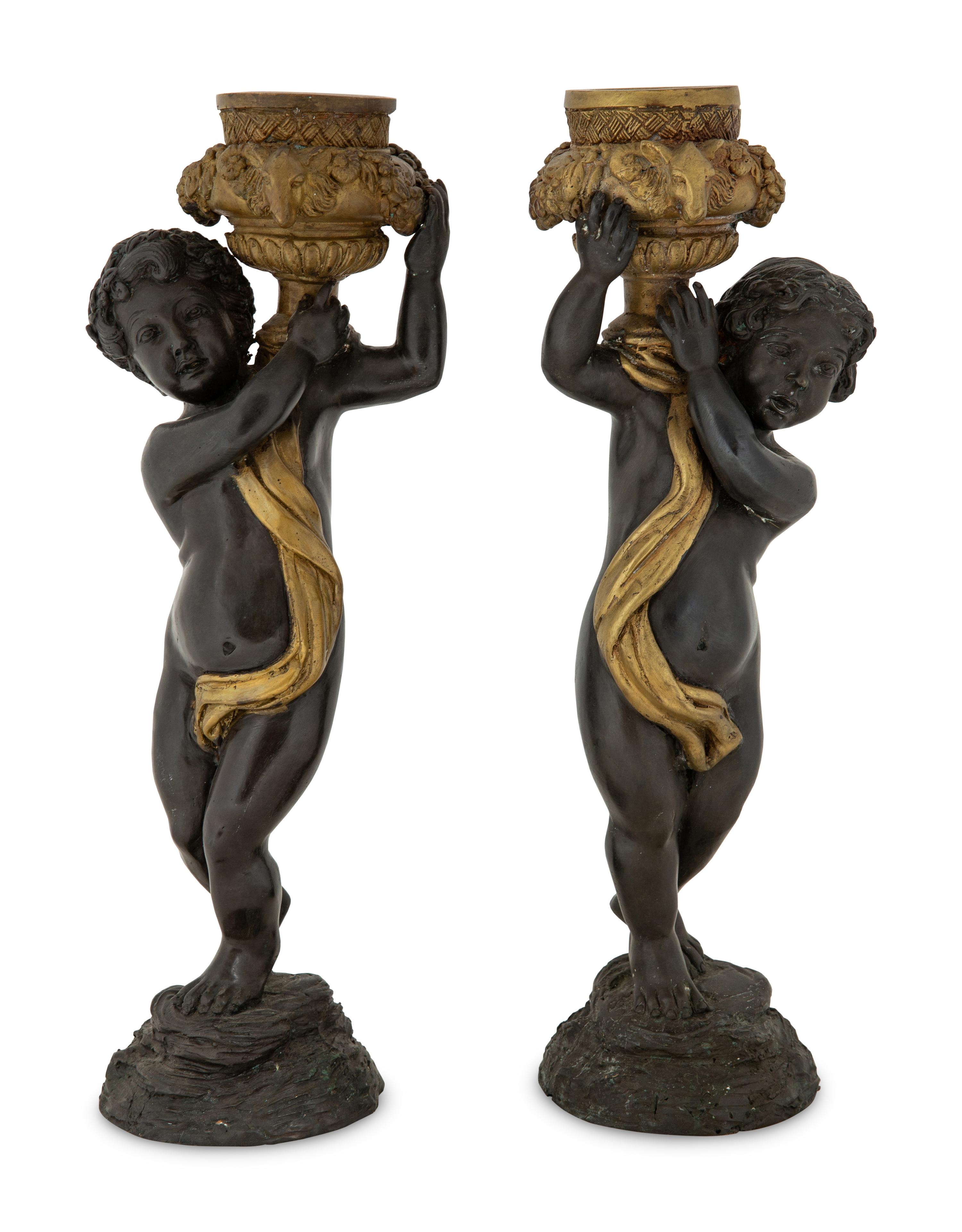 A Pair of Parcel Gilt Cast Metal Putti Candlesticks