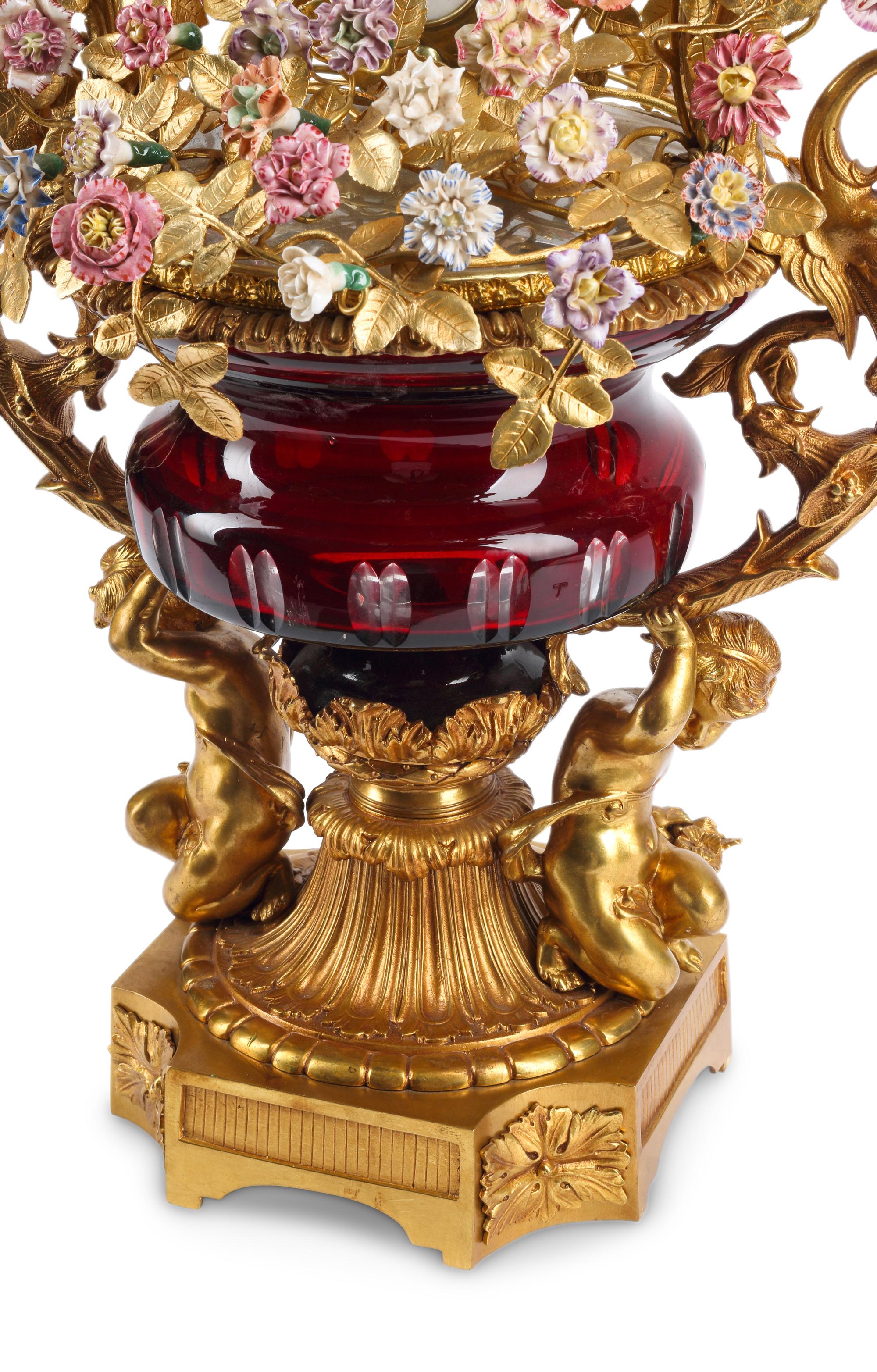 A Louis XV Style Red Cut Glass, Gilt Bronze and Porcelain Clock