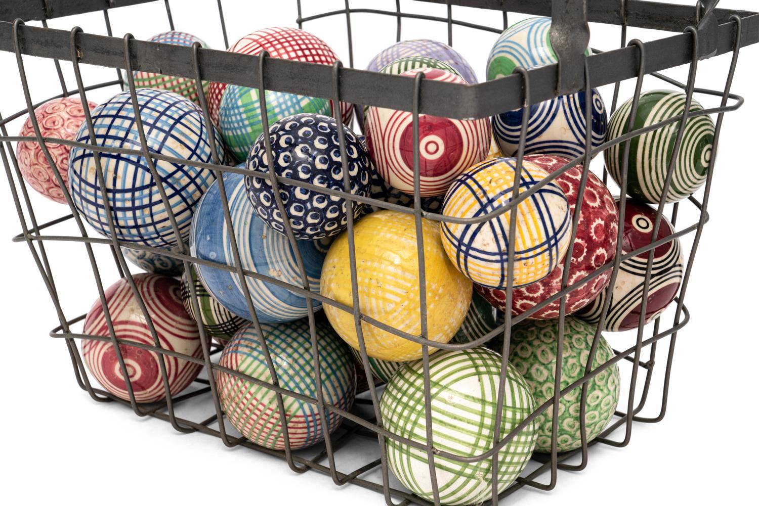 A Collection of English Polychrome Glazed Carpet Balls in a Wirework Basket