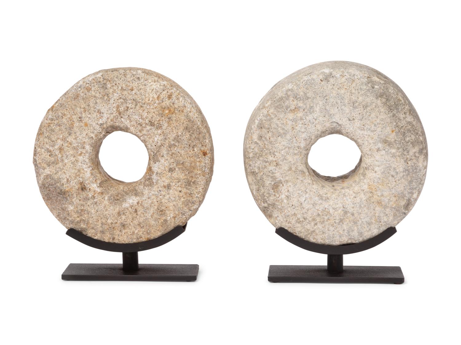 Two Millstone Disks on Metal Stands