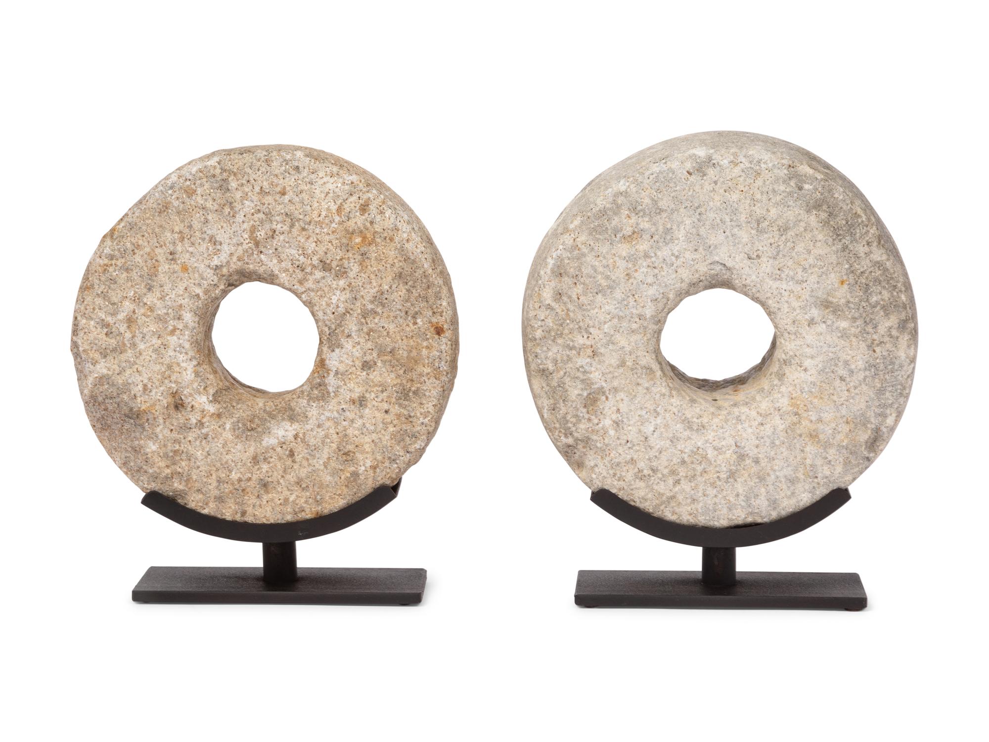 Two Millstone Disks on Metal Stands