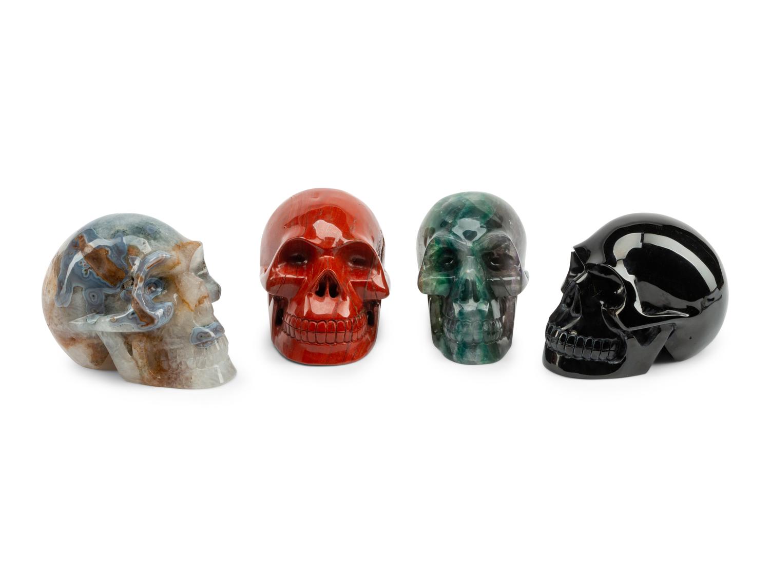 A Set of Four Carved Agate, Fluorite, Red Jasper and Black Obsidian Skulls