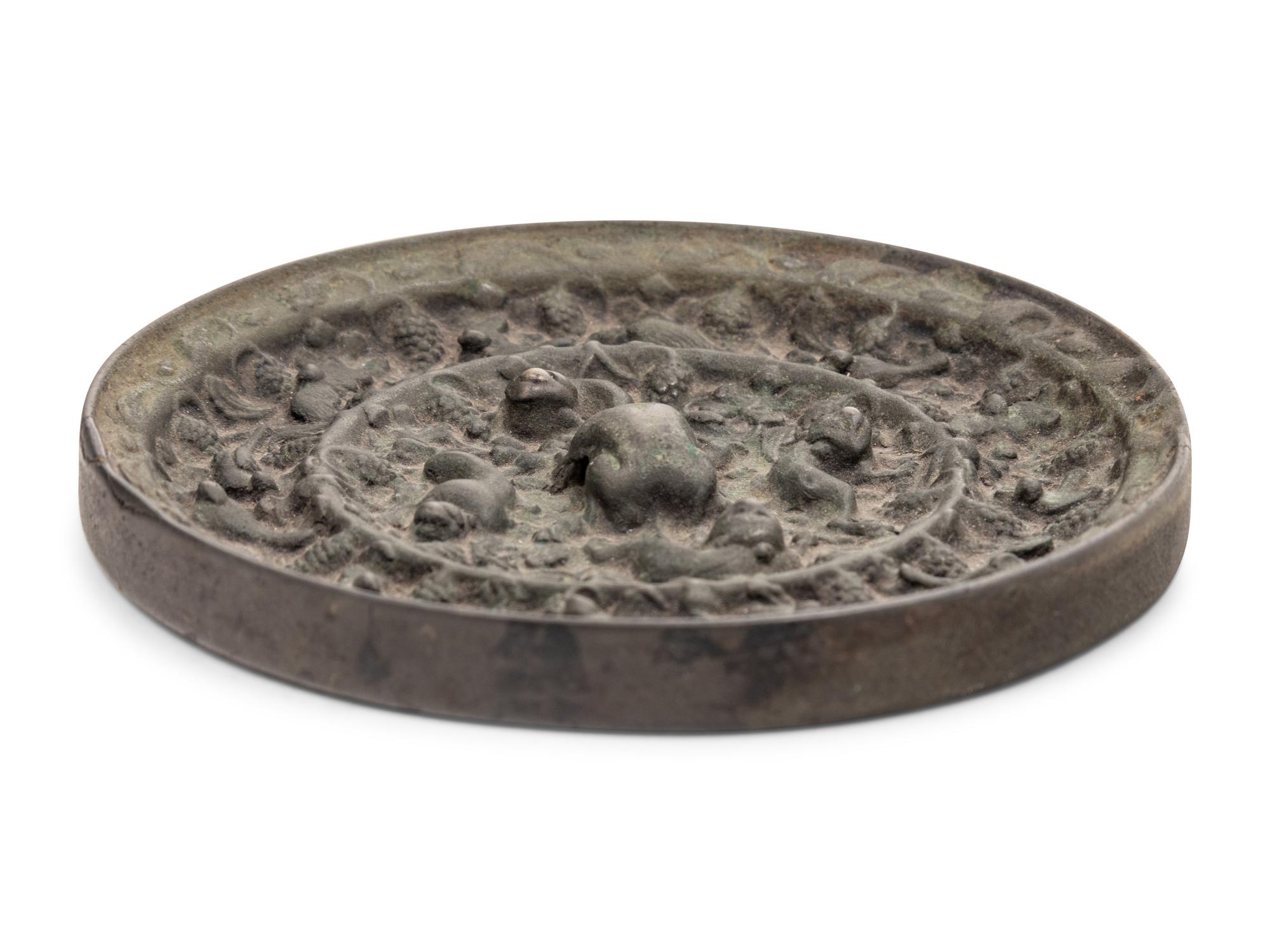 A Chinese Bronze Circular 'Mythical Beasts and Grapes' Mirror