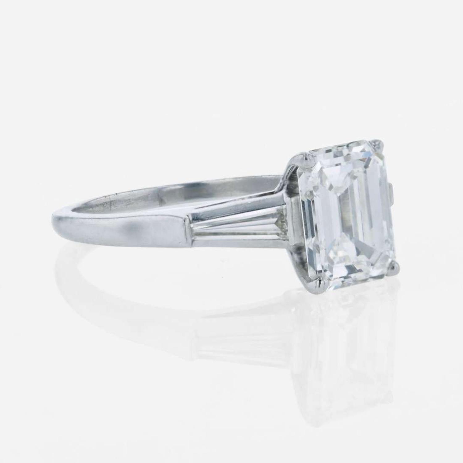 An emerald-cut diamond accented solitaire ring