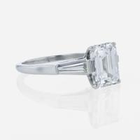 An emerald-cut diamond accented solitaire ring