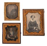 [EARLY PHOTOGRAPHY]. A group of 23 daguerreotypes featuring subjects posed with cased images, including: