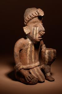 A Nayarit Terracotta Crouching Figure with Vessel