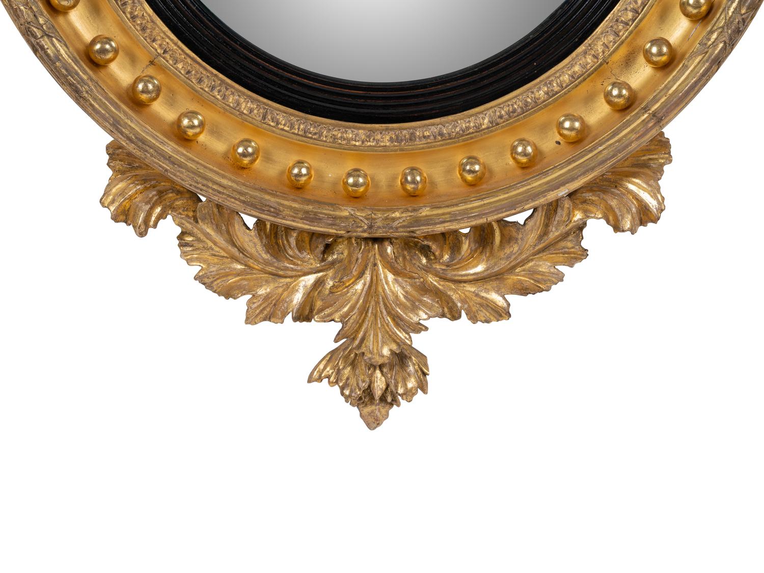 A Regency Parcel Ebonized Giltwood Convex Girandole Mirror