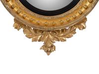 A Regency Parcel Ebonized Giltwood Convex Girandole Mirror