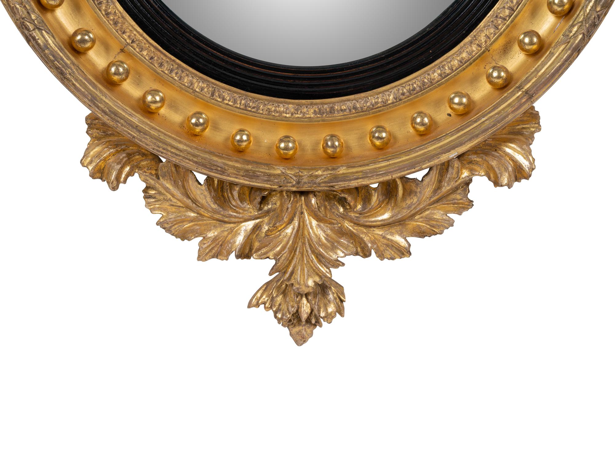 A Regency Parcel Ebonized Giltwood Convex Girandole Mirror