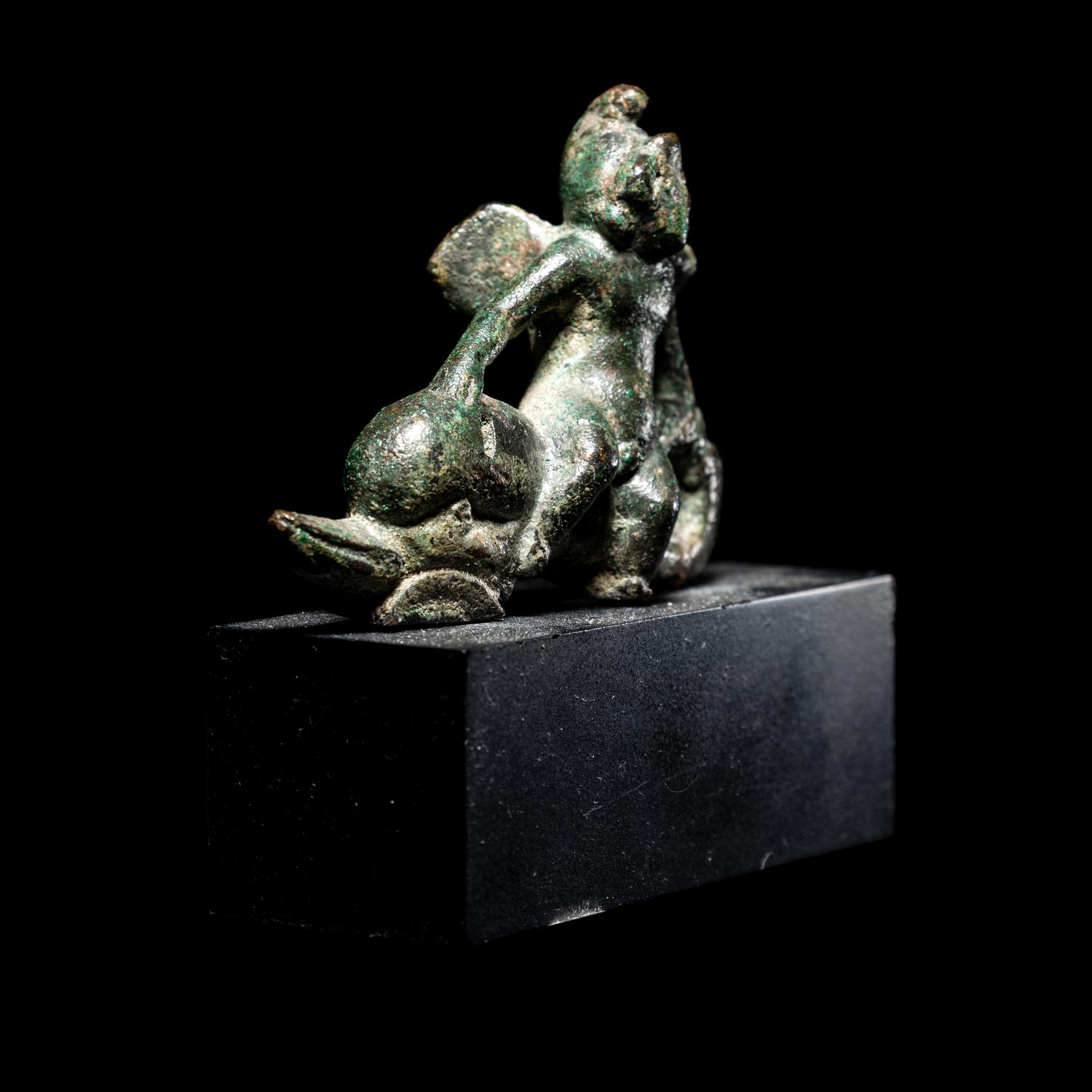 A Roman Bronze Eros Riding a Dolphin