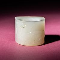 A Chinese Russet and White Jade 'Taotie and Chilong' Archer's Ring, 18th Century — 清中期 白玉留皮饕餮螭龍紋扳指