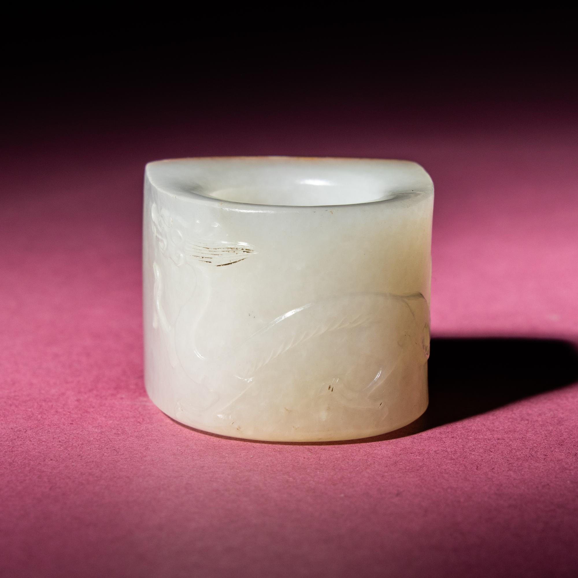 A Chinese Russet and White Jade 'Taotie and Chilong' Archer's Ring, 18th Century — 清中期 白玉留皮饕餮螭龍紋扳指