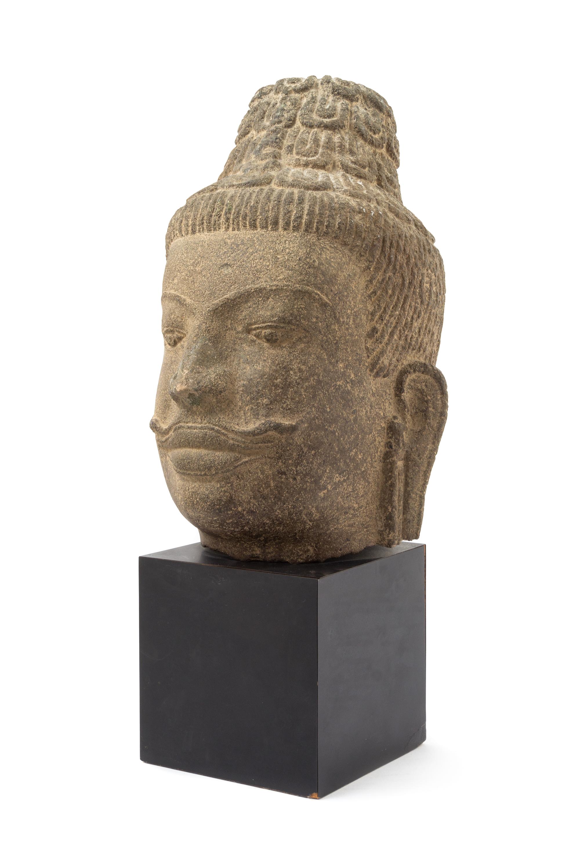 A Southeast Asian Stone Head of a Bodhisattva 17TH CENTURY OR EARLIER Height overall 18 inches. — 17TH CENTURY OR EARLIER