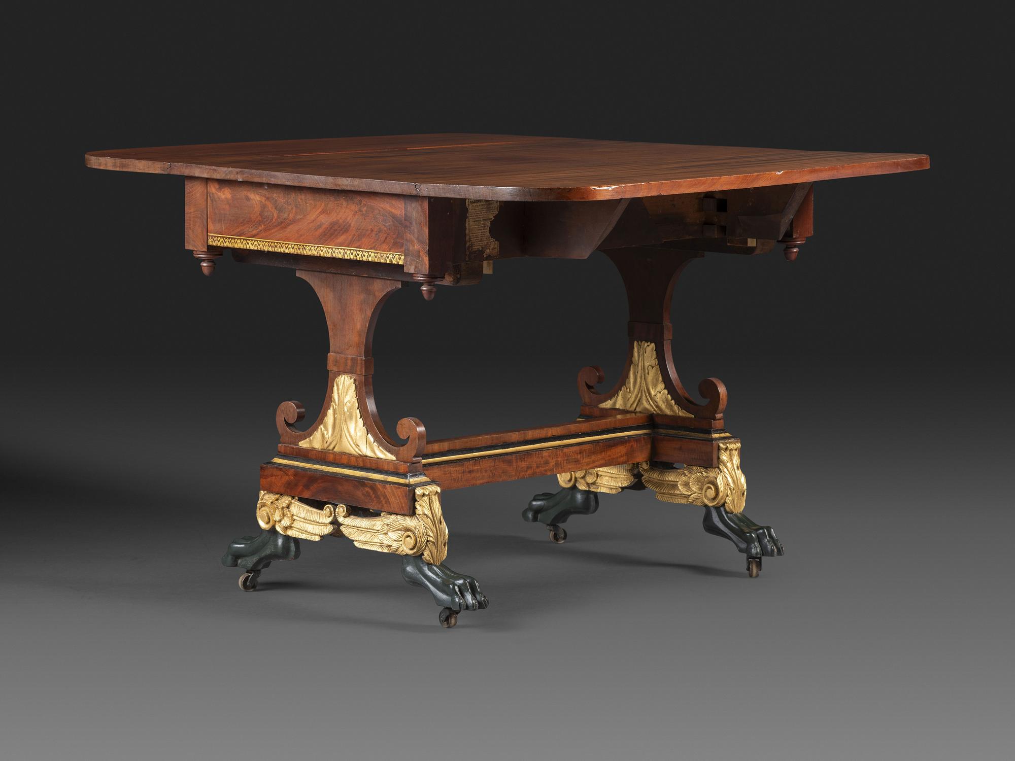 A Classical Parcel Gilt and Ebonized, Figured Mahogany Paw-Foot Drop-Leaf Table