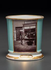 A Paint Enhanced Photographic Transfer Porcelain Occupational Shaving Mug Depicting a Tailor's Shop