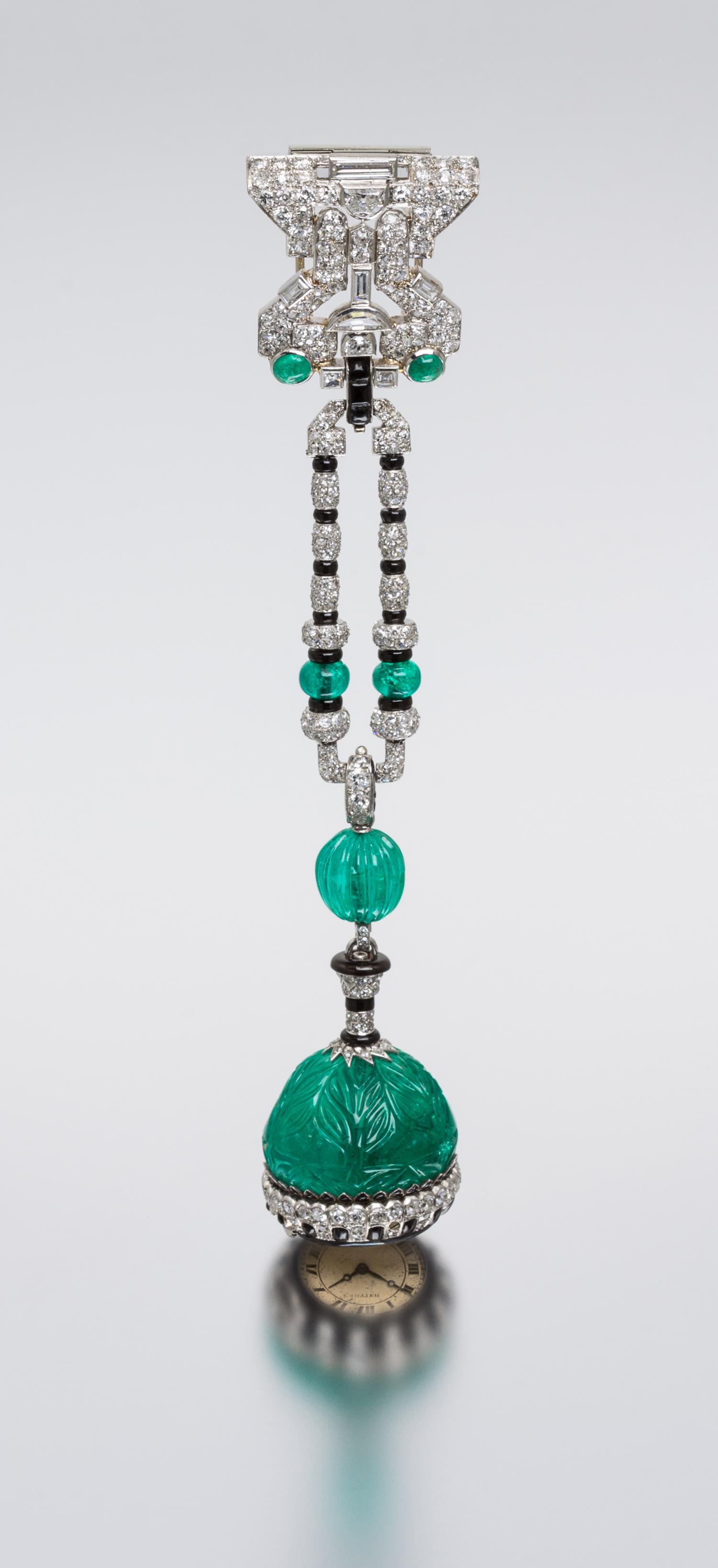 An Art Deco Platinum, Emerald, Diamond, Onyx and Enamel Lapel Watch, Cartier, 37.00 dwts.