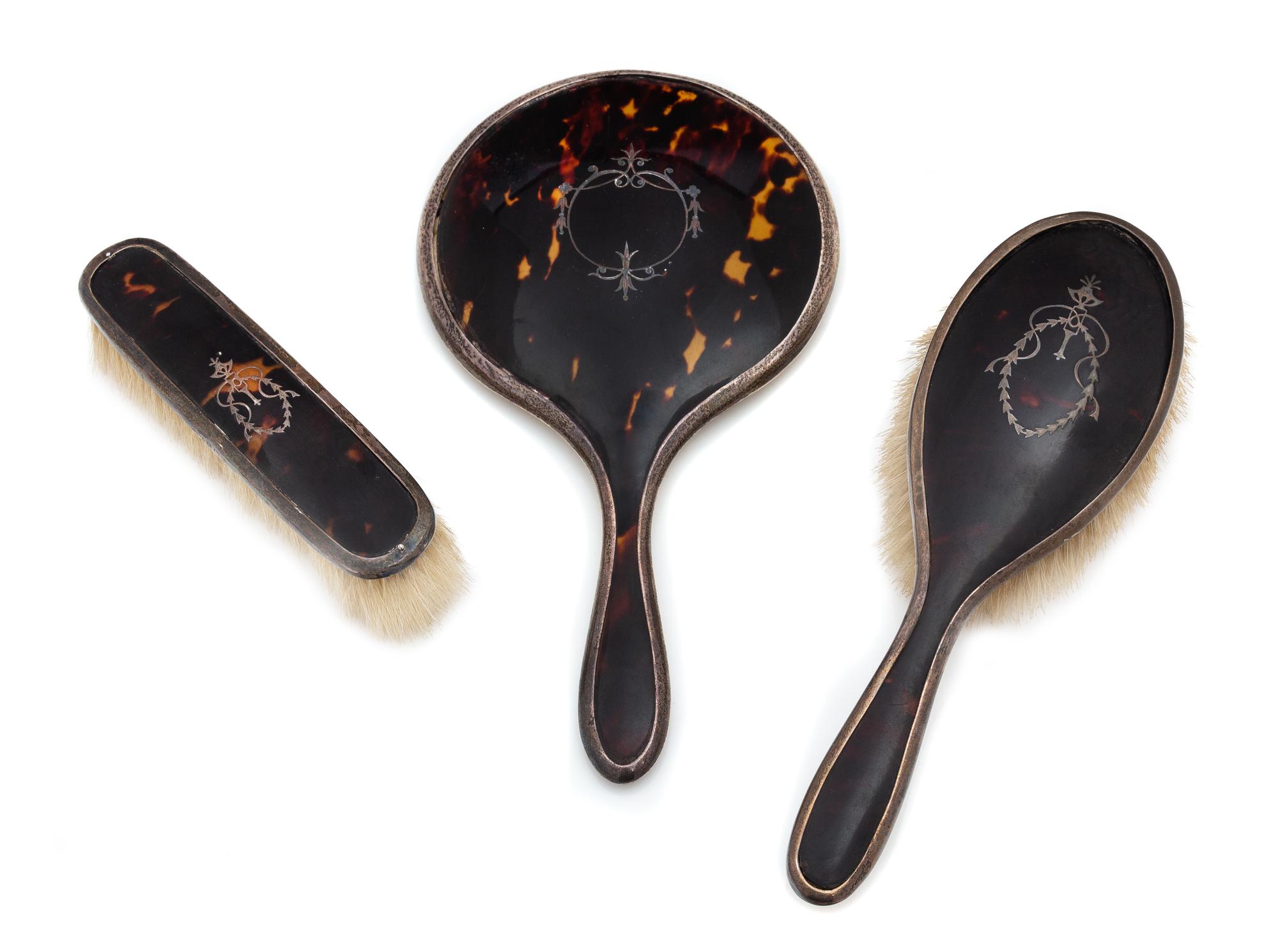 An English Silver and Tortoise Shell Three-Piece Dresser Set, G. W. Lewis & Co., Birmingham, 1919-25, comprising two brushes and a hand