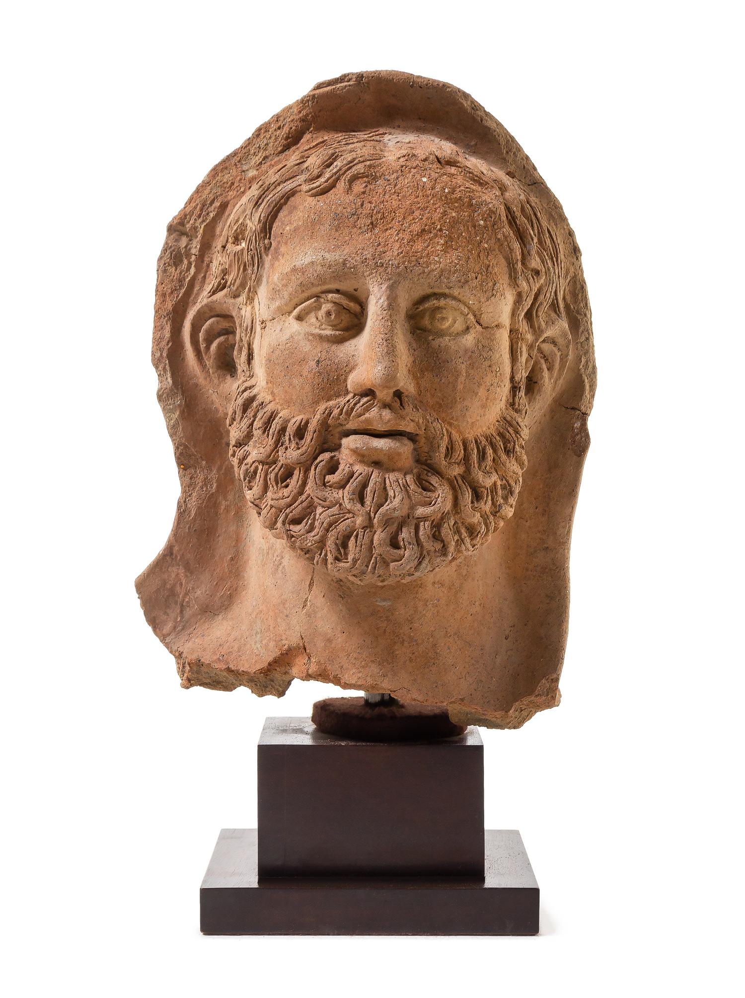 An Etruscan Terra Cotta Votive Head of a Bearded Man Height 12 1/4 inches. — CIRCA 4TH-3RD CENTURY B.C.E.