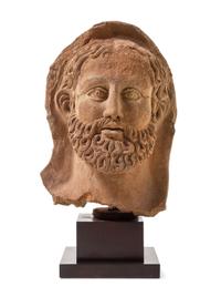 An Etruscan Terra Cotta Votive Head of a Bearded Man Height 12 1/4 inches. — CIRCA 4TH-3RD CENTURY B.C.E.