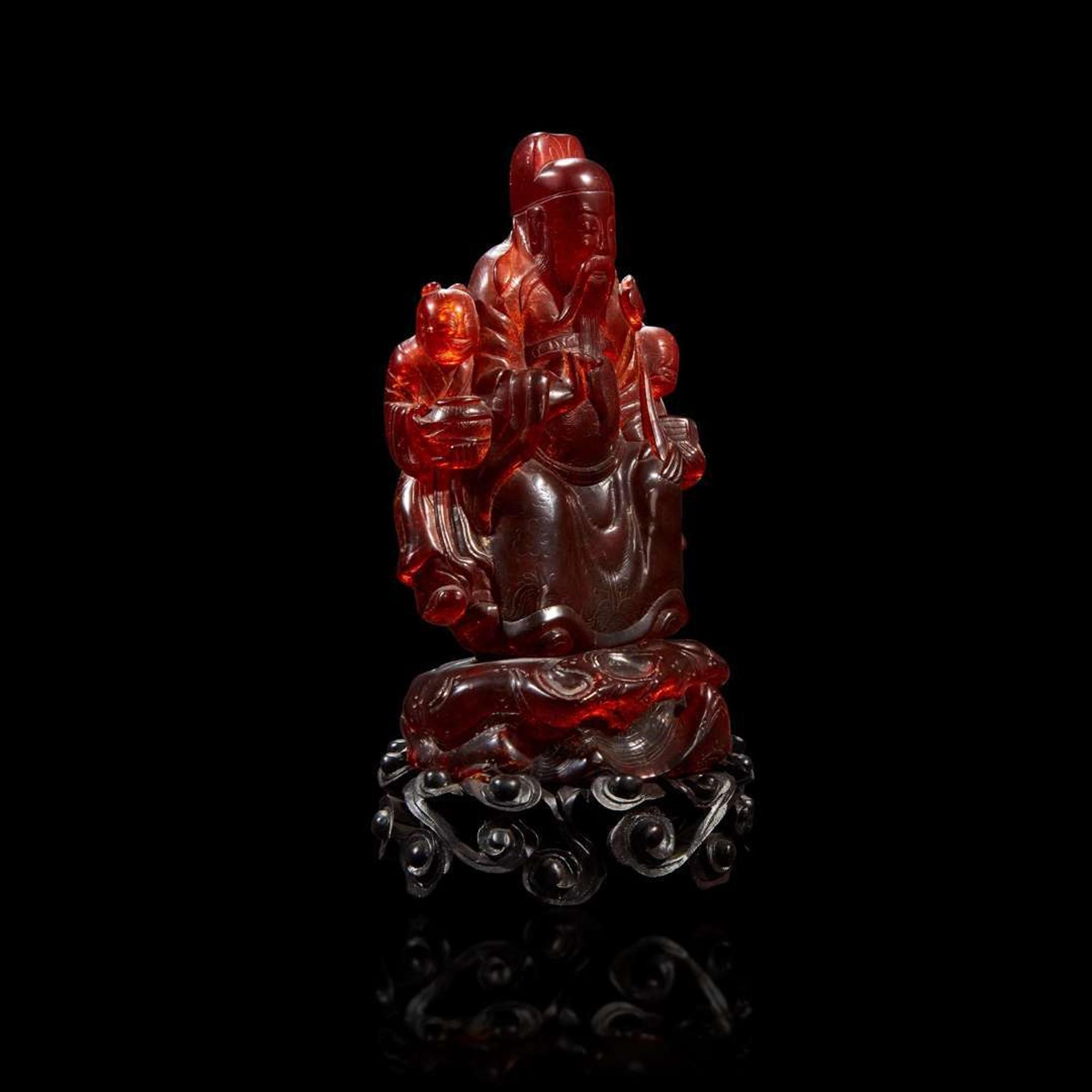 A Chinese carved amber figure of a sage and acolytes
