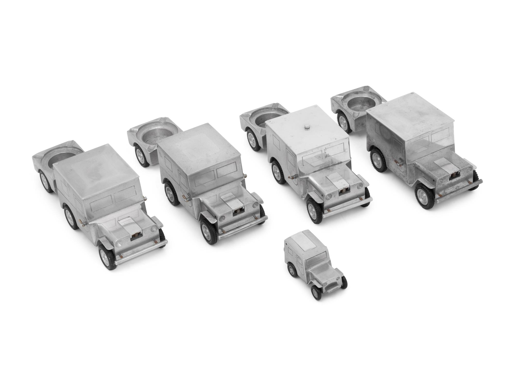 A Set of Four German Vehicle-Form Metal Cigarette Box, Lighter and Ashtray Sets