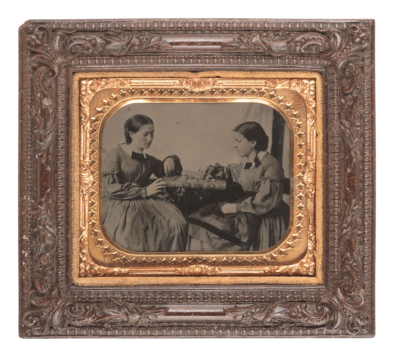 [EARLY PHOTOGRAPHY]. Sixth plate tintype of identified women engaged in a game of checkers. Ca 1863.