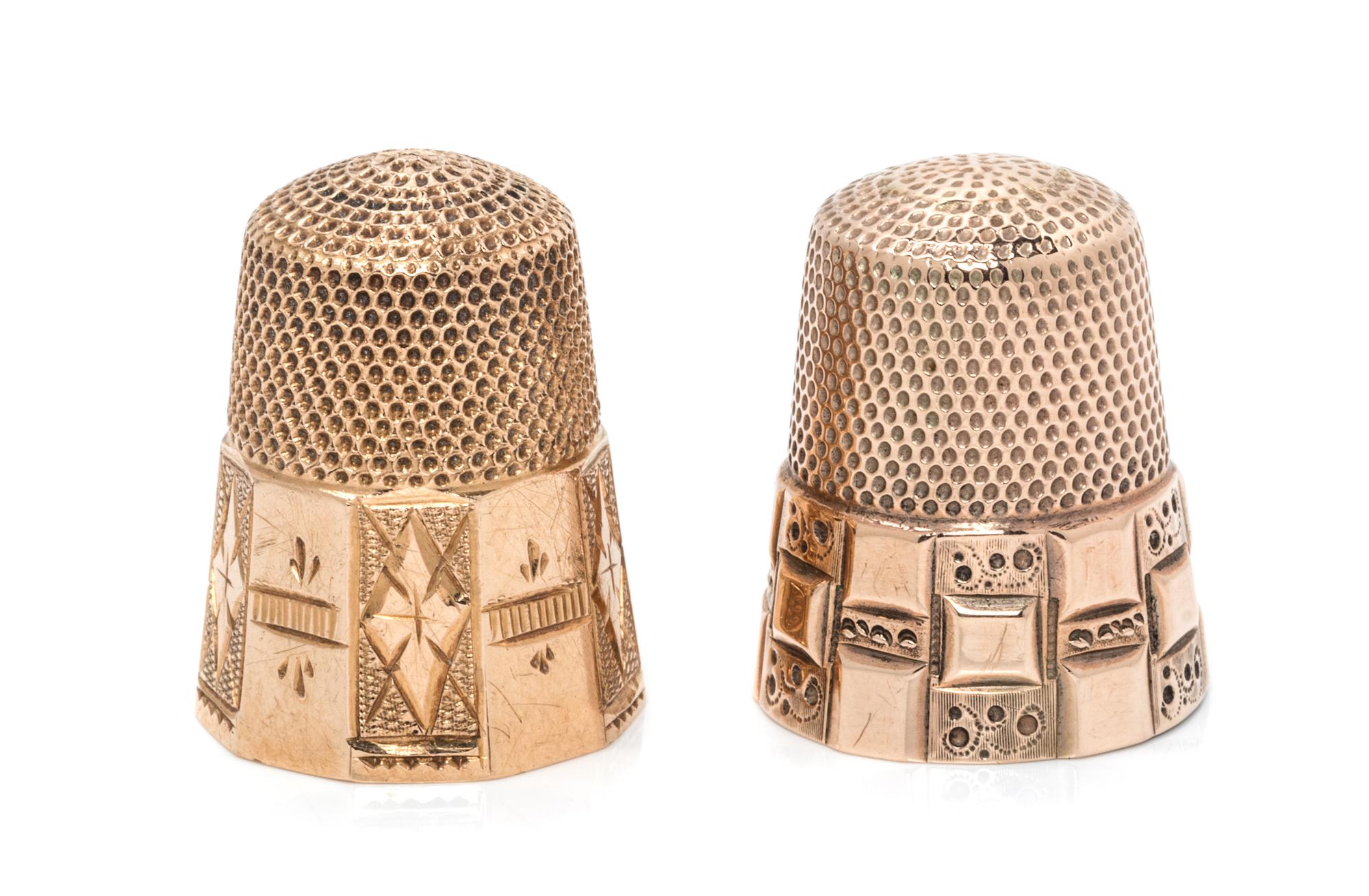 Two American Gold Thimbles, , each having a knurled top and body above a paneled base, each with foliate and geometric motifs.