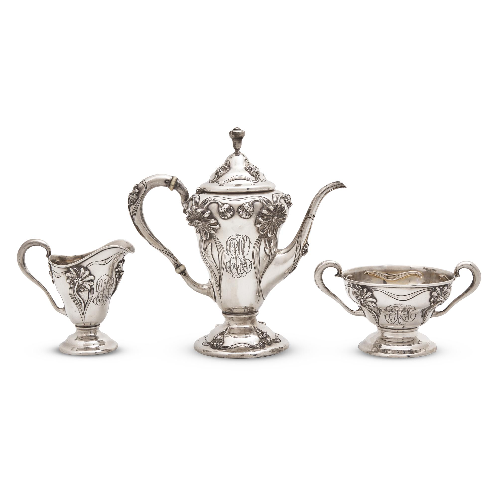 An Art Nouveau Three-Piece Sterling Silver Floral Cast and Repousse Coffee Service