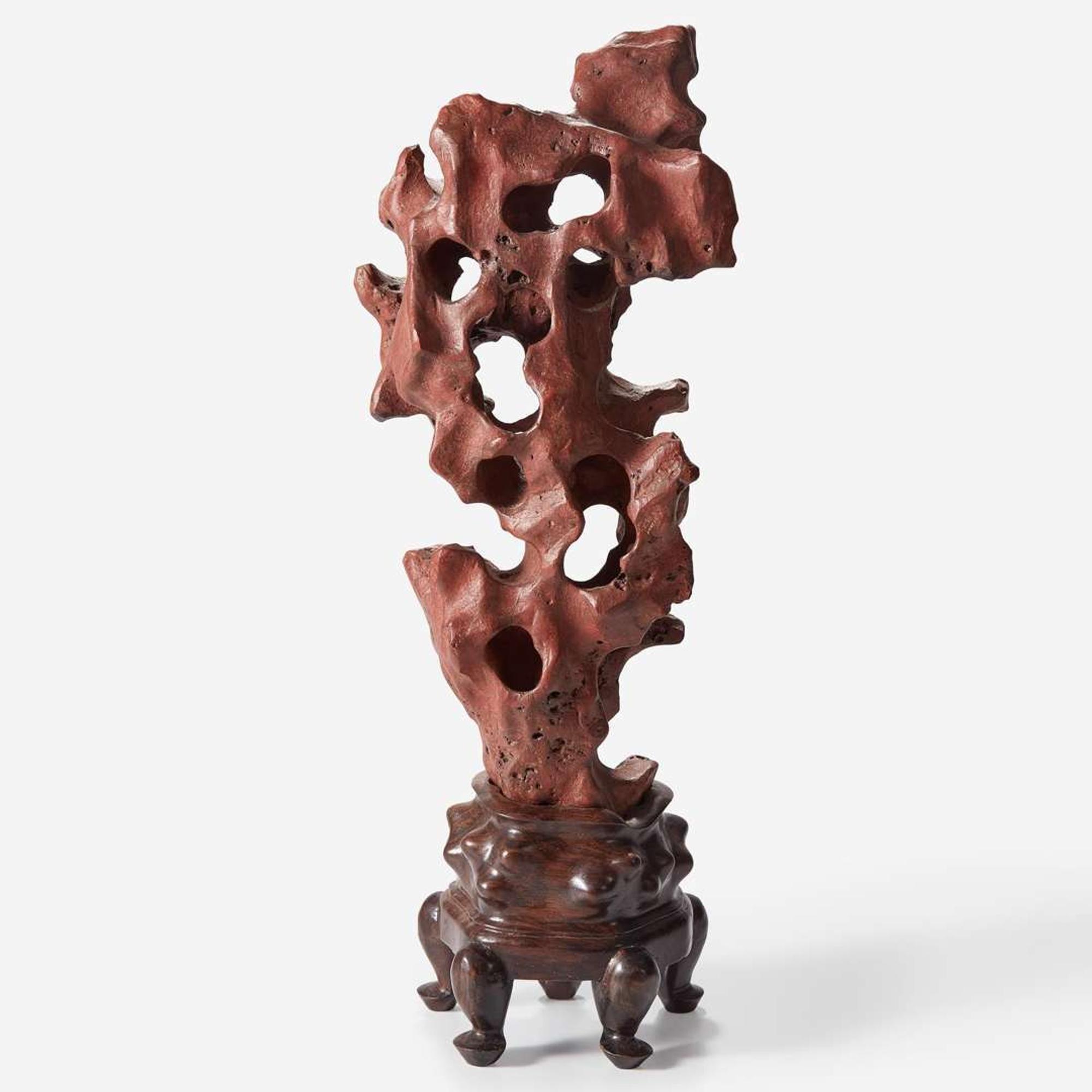 A Chinese scholar's rock on wood stand, possibly red Taihu stone