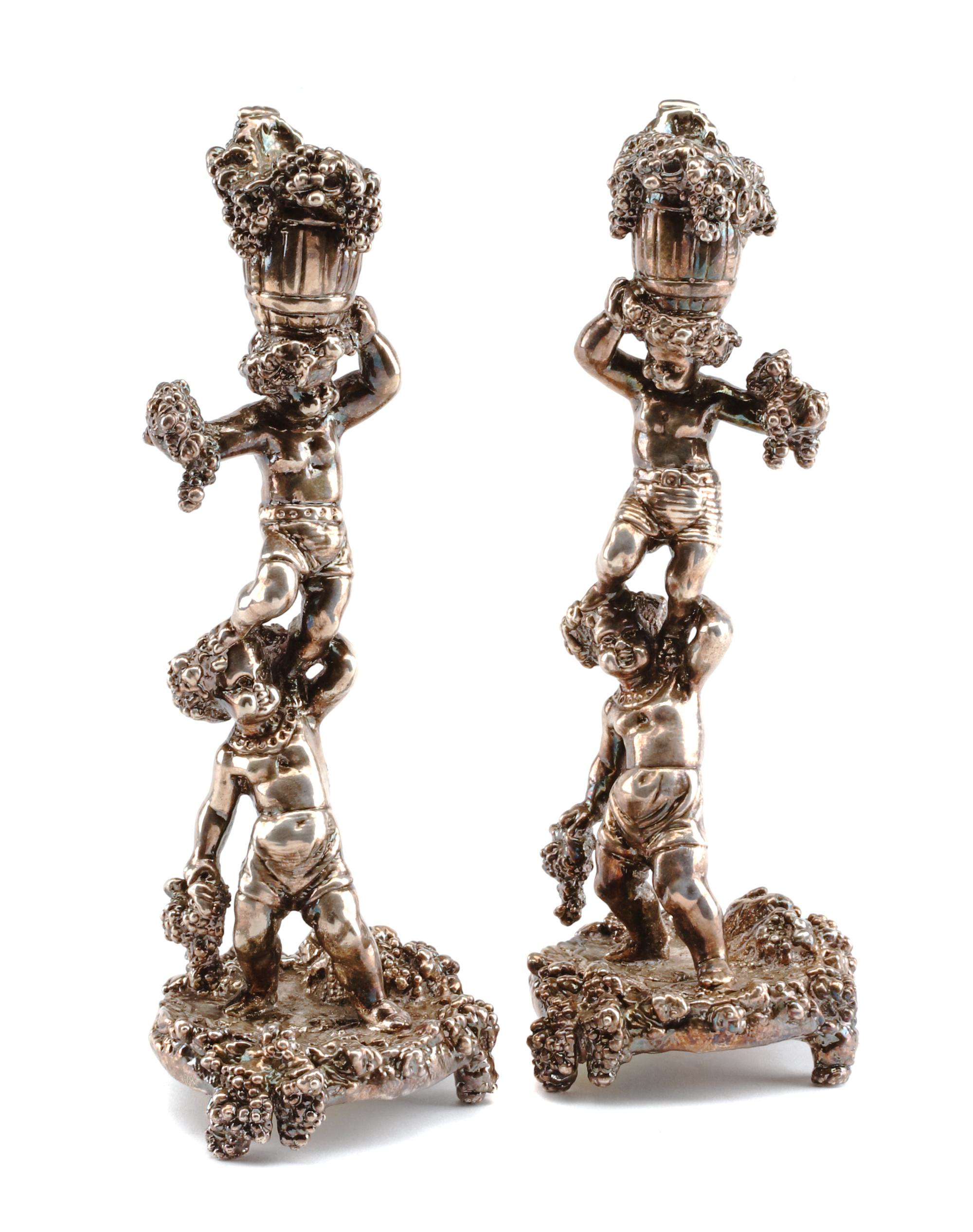 A Pair of Silver Figural Candlesticks, Circa 2000, each in the form of two Bacchanalian putti supporting a bushel of grape bunches, wei
