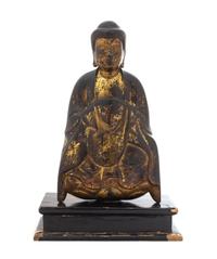 A Gilt and Black Lacquered Wood Figure of a Seated Shakyamuni Buddha Height of figure 12 1/4 inches.