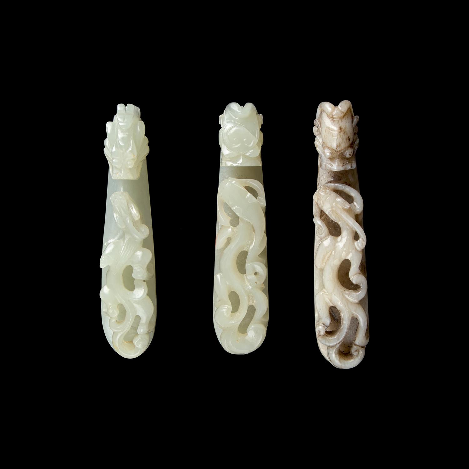 A Chinese 'Chicken-Bone' Jade and Two Pale Celadon Jade 'Dragon' Belt Hooks, Qing Dynasty 清 玉龍鉤三件