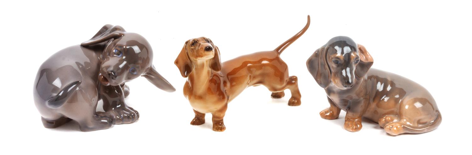A Group of Three Dachshund Porcelain Figures Width of widest 5 1/8 inches.
